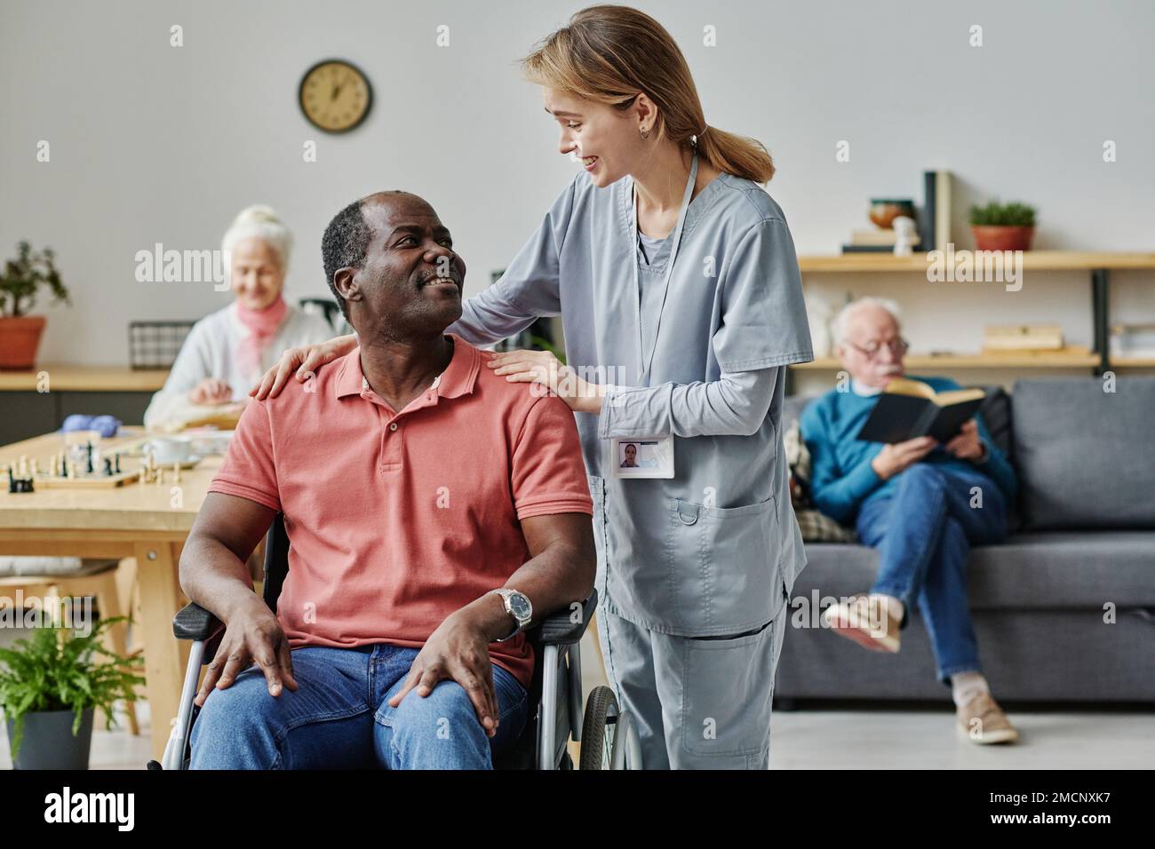 Volunteer talking to African American man with disability in the room ...