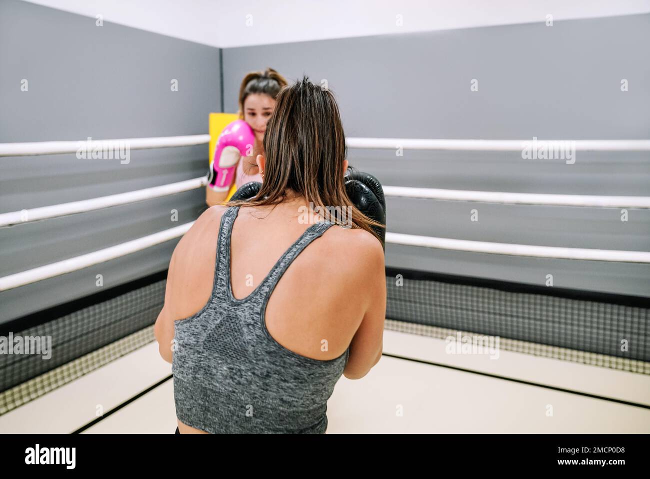 Two female boxers fighting in a boxing practice on top of a ring Stock
