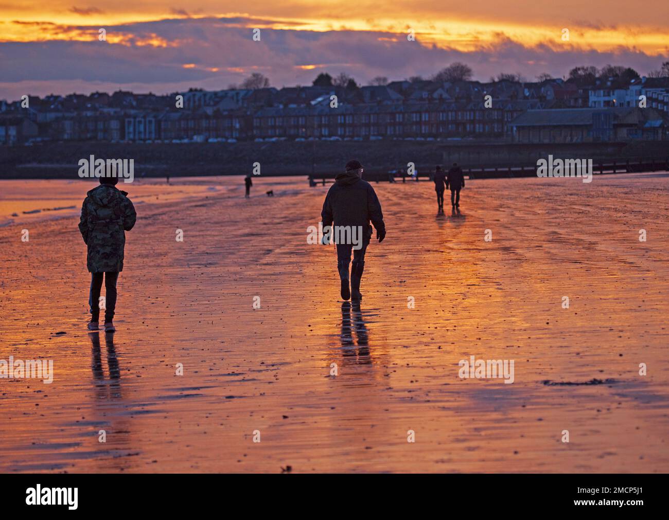 Portobello, Edinburgh, Scotland, UK. 22 January 2023. Fiery sunrise by the Firth of Forth with a slighlty milder but still nippy temperature of 5 degrees centigrade for those out and about at the seaside. Pictured: People take an early morning stroll along the shore. Credit: Scottishcreative/alamy live news. Stock Photo