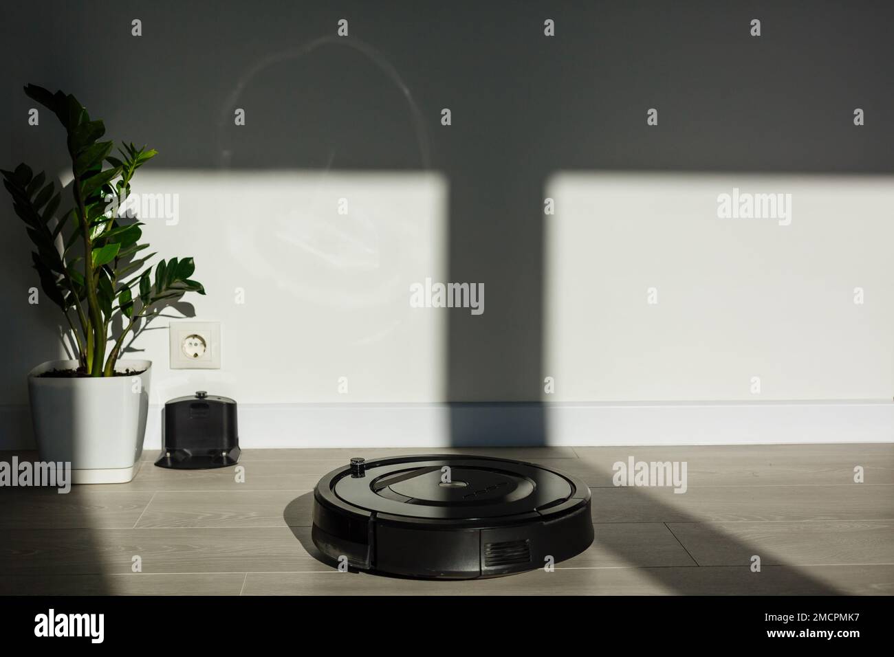 The robot vacuum cleaner drives on the laminate floor. Smart House