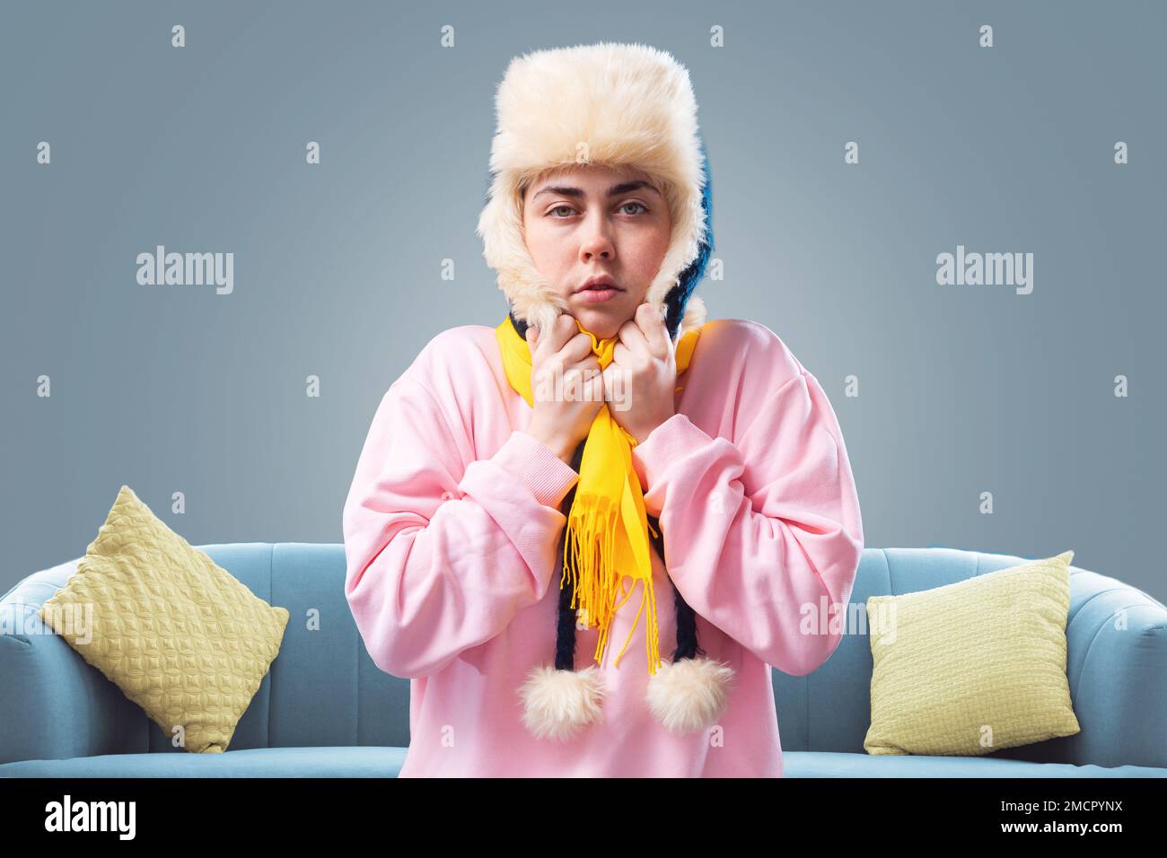 Young freezed woman in ushanka hat and yellow scarf is warming herself ...