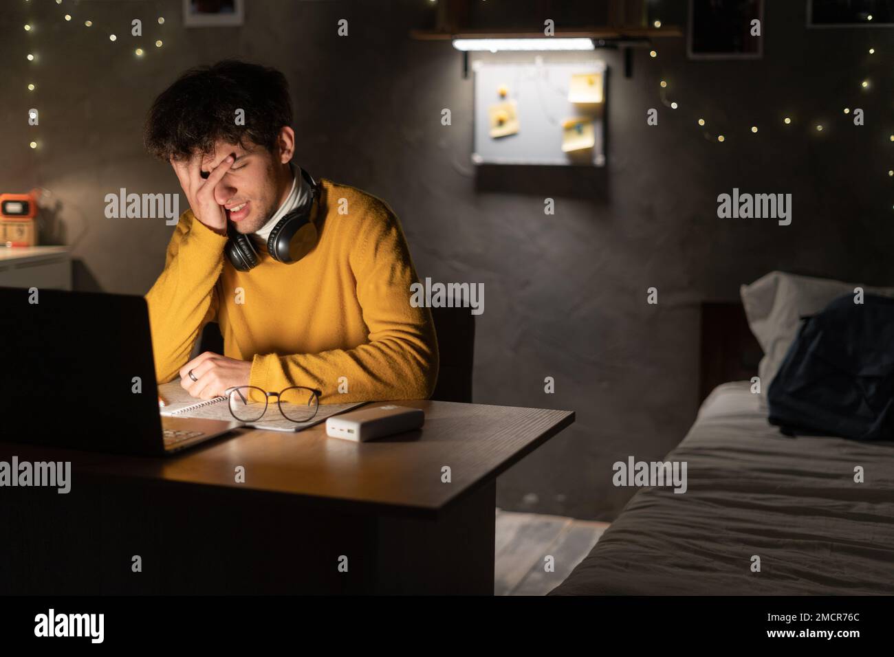 Worried and sad student male searching information in a laptop online in a desk at home or dormitory room. Copy space Stock Photo