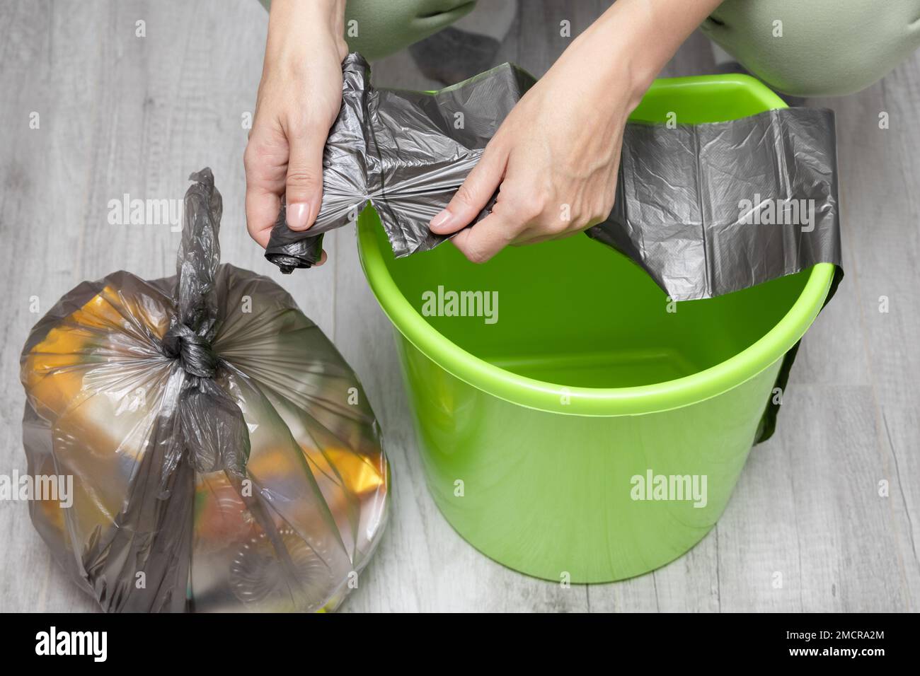 a man changes a garbage bag in a bucket. woman changing trash bag