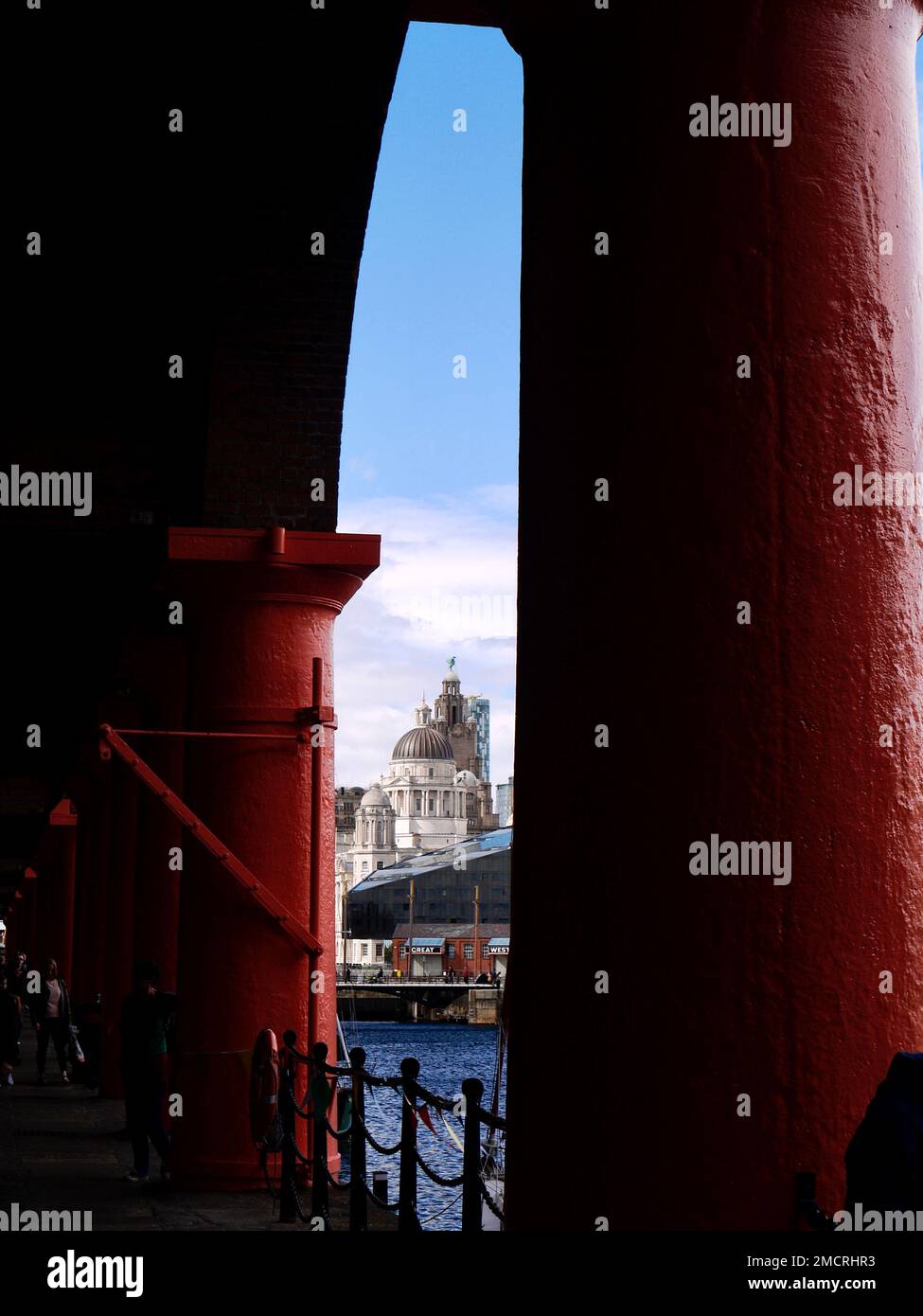 The Liver Building as seen through the imposing red painted columns of the refurbished Royal Albert Dock, Liverpool Stock Photo