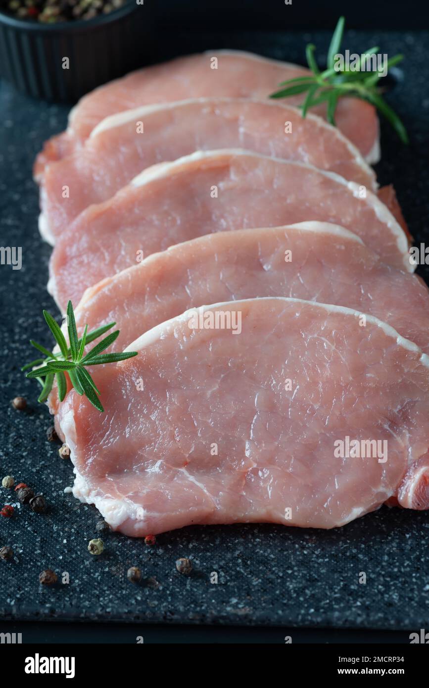 https://c8.alamy.com/comp/2MCRP34/sliced-raw-pork-meat-on-a-dark-cutting-board-2MCRP34.jpg