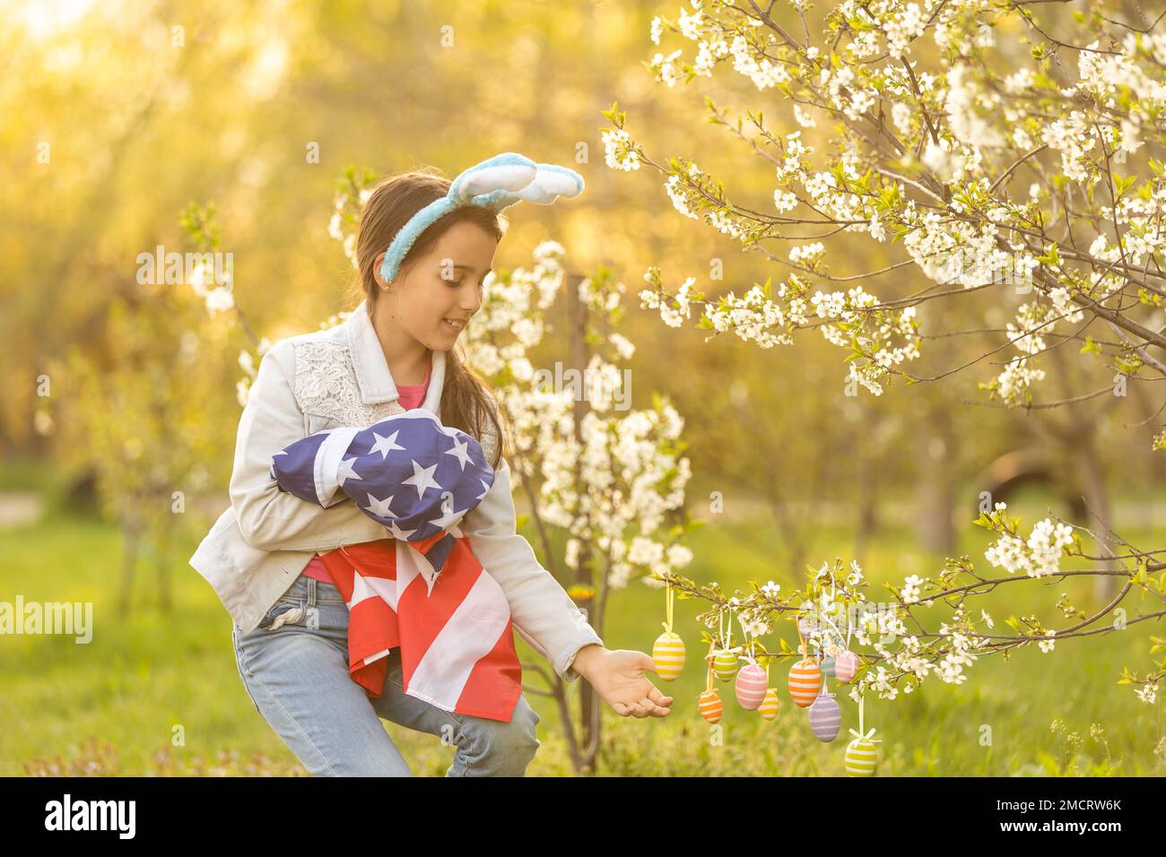 A teenage girl in a blooming garden at Easter with a US flag Stock ...