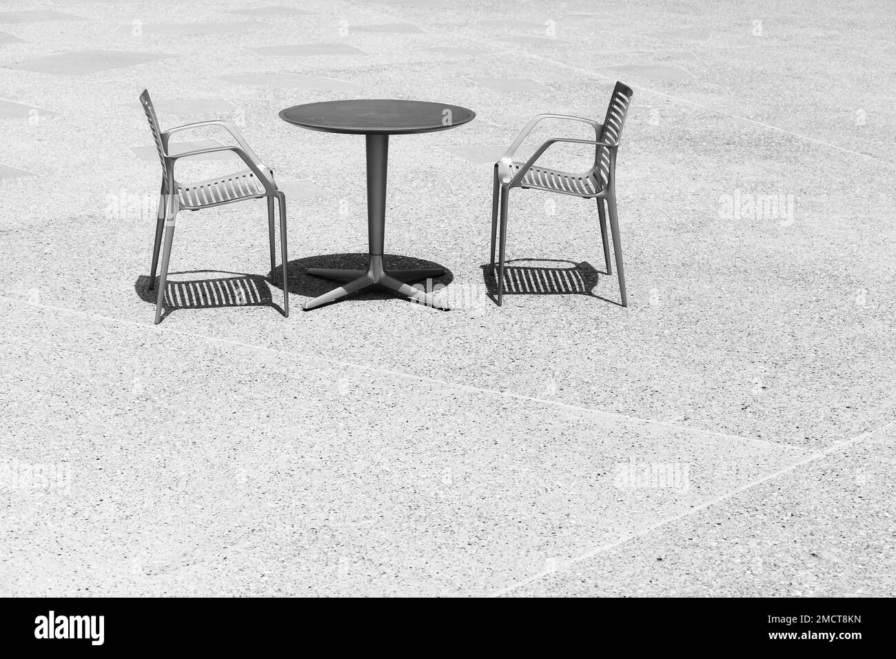 Black and white photo of two chairs at an empty table, space for text