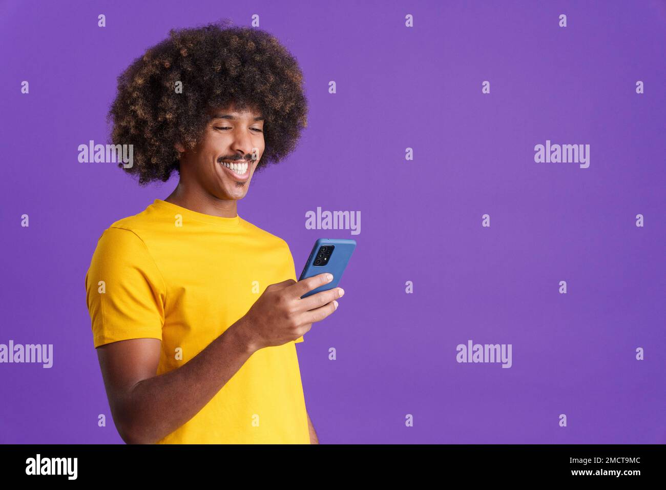 Happy african man smiling while using a mobile Stock Photo