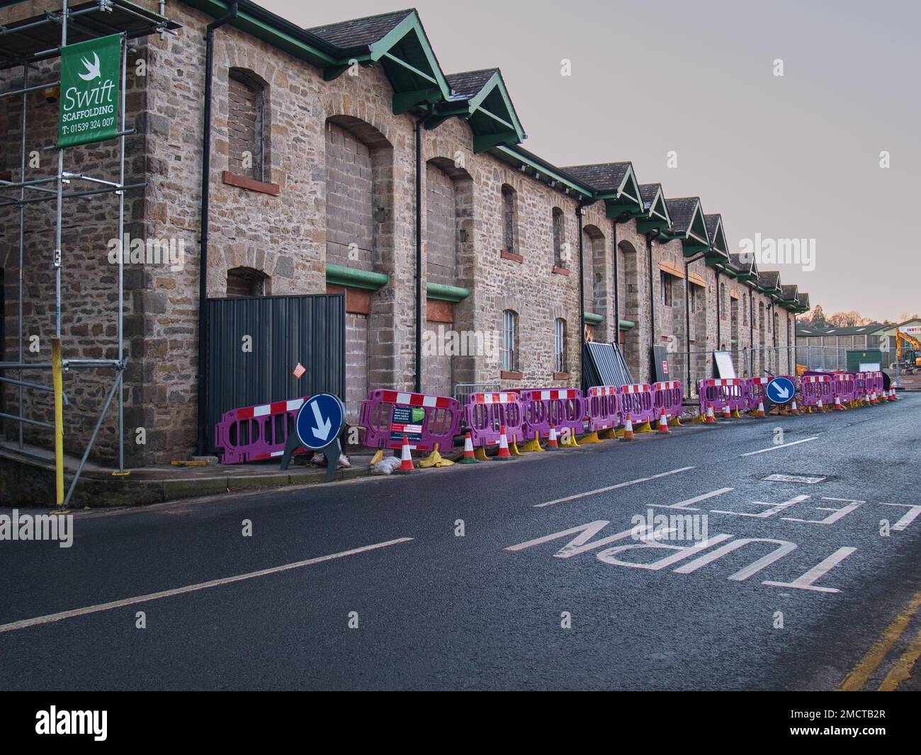 Safety barriers surrounding the old bonded warehouse during its conversion to a Lidl store in Kendal, UK. Lidl is a German discount supermarket expand Stock Photo