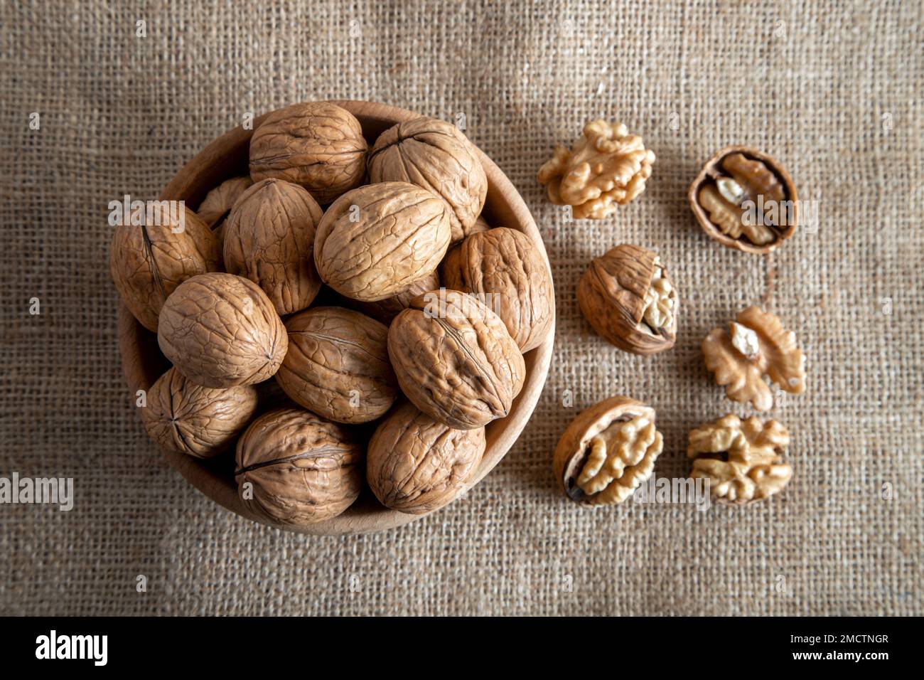 Peel walnuts and whole walnuts on burlap sack Stock Photo
