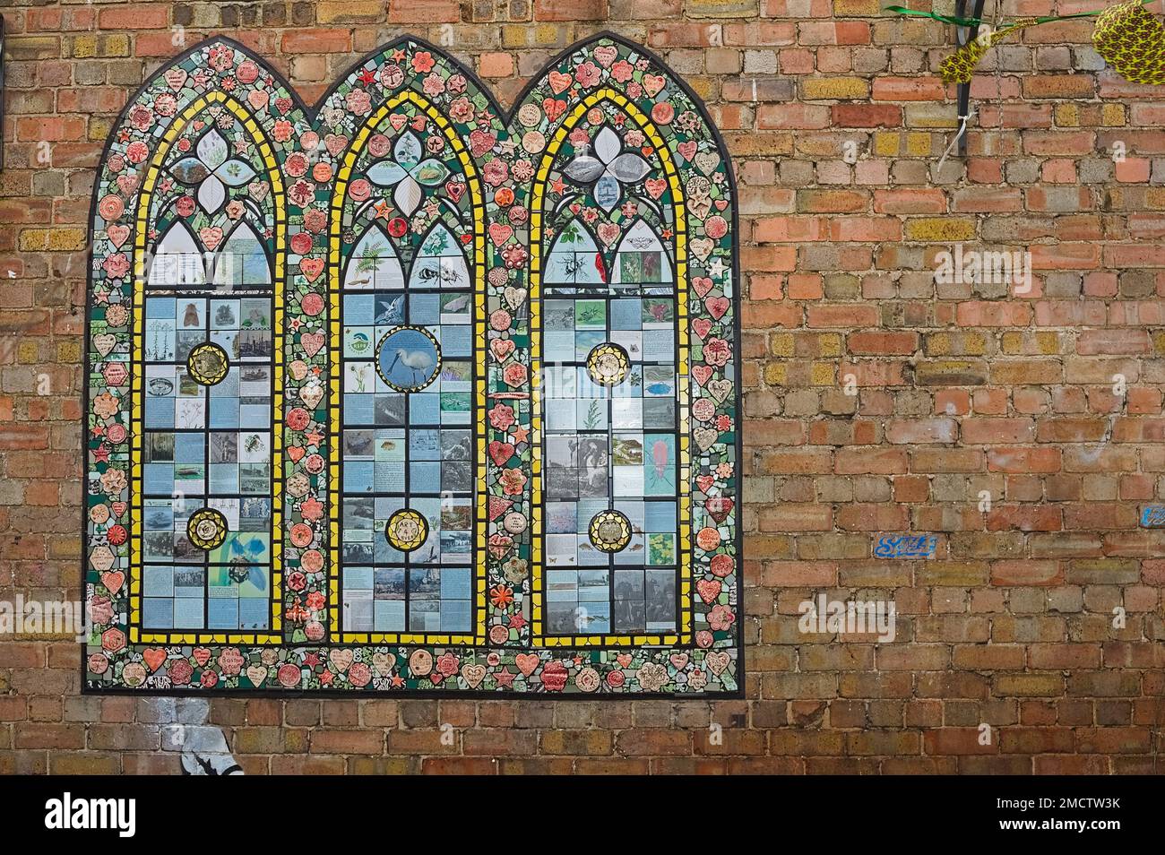 mural of a stained glass window on a brick wall in town Stock Photo