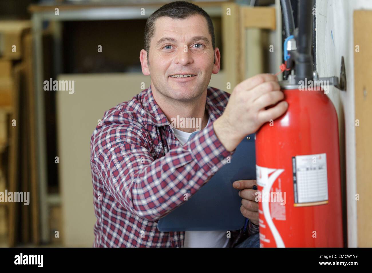 happy male professional checking a fire extinguisher Stock Photo