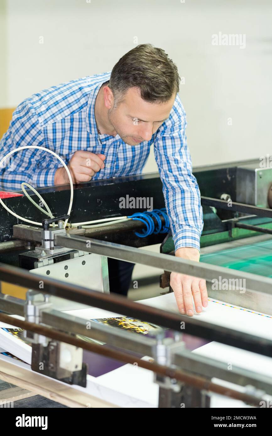 engineer leaning over printing machine Stock Photo Alamy