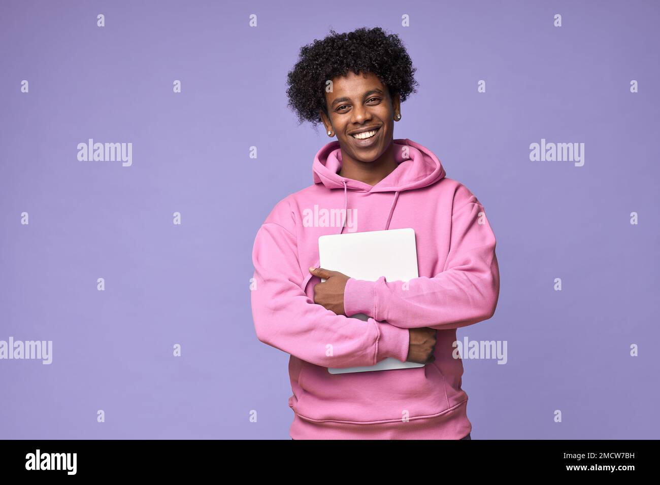 Happy African teen student holding laptop isolated on purple background. Stock Photo