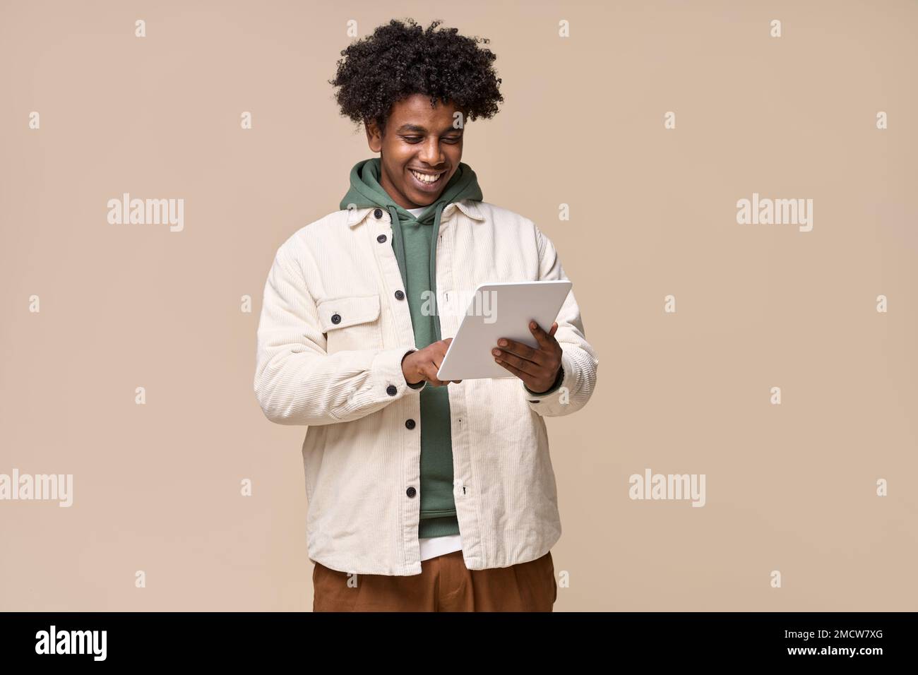 Happy African teenager holding using tablet isolated on beige background. Stock Photo
