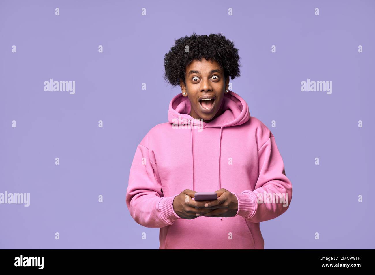 Excited amazed African teen guy using mobile phone winning online. Stock Photo
