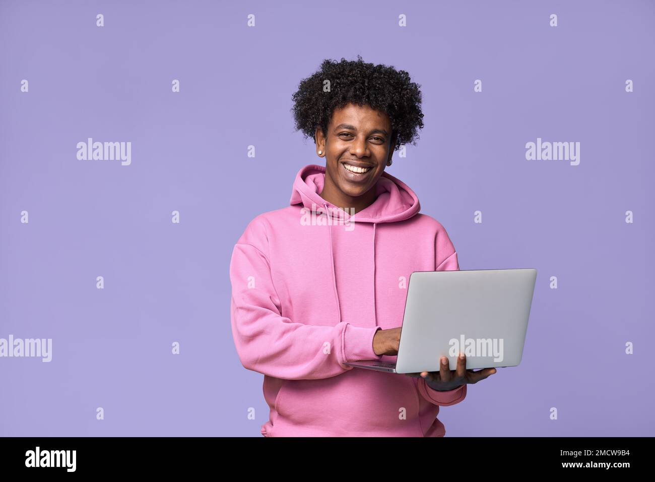 Happy African teenager holding using laptop isolated on purple background. Stock Photo