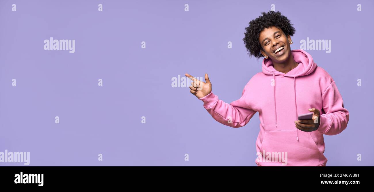 Happy African teenager holding mobile phone pointing finger presenting app. Stock Photo