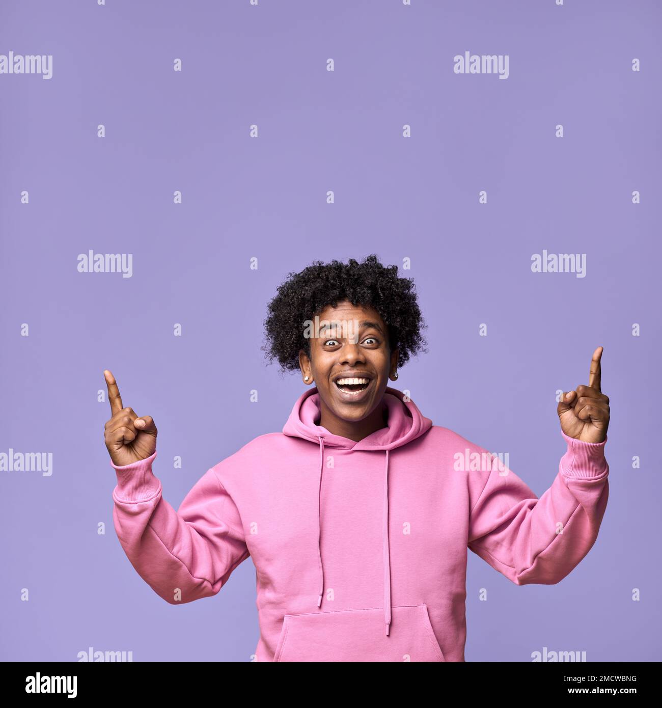 Happy surprised African teen guy looking pointing up presenting promotion. Stock Photo