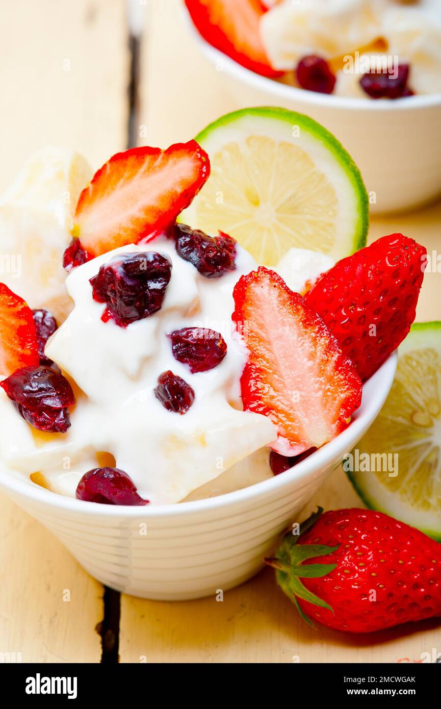 Fruit and yogurt salad healthy breakfast over white wood table Stock