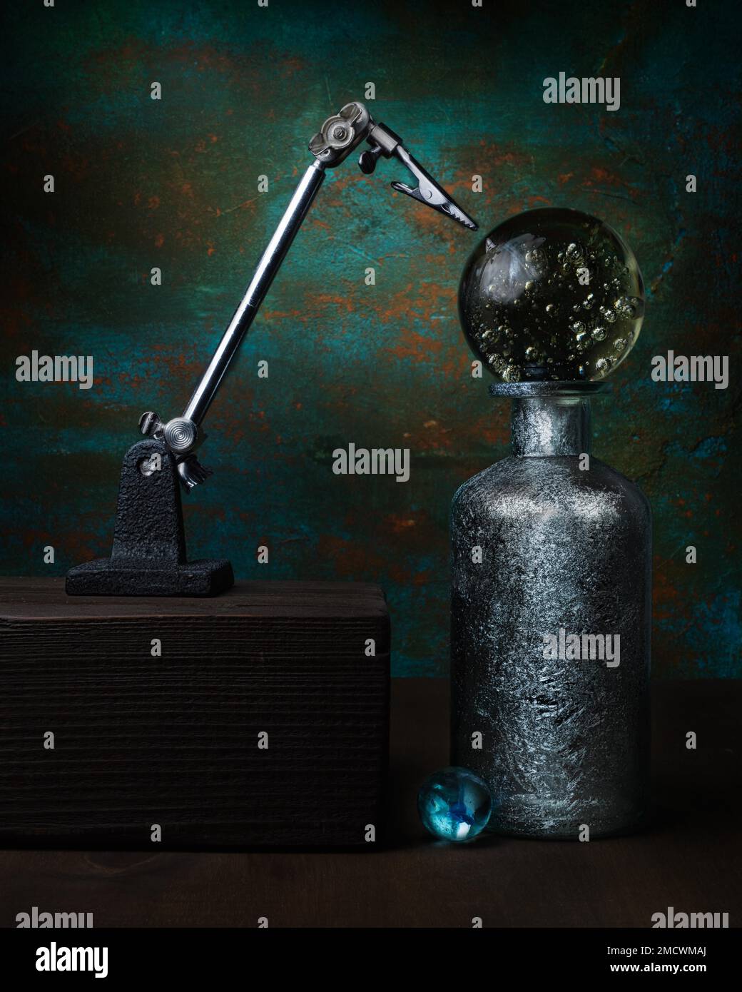 Topic Mysticism, Superstition, Astrology, Still life with glass ball on silver bottle next to auxiliary tool Third hand, Studio shot, Symbol photo Stock Photo