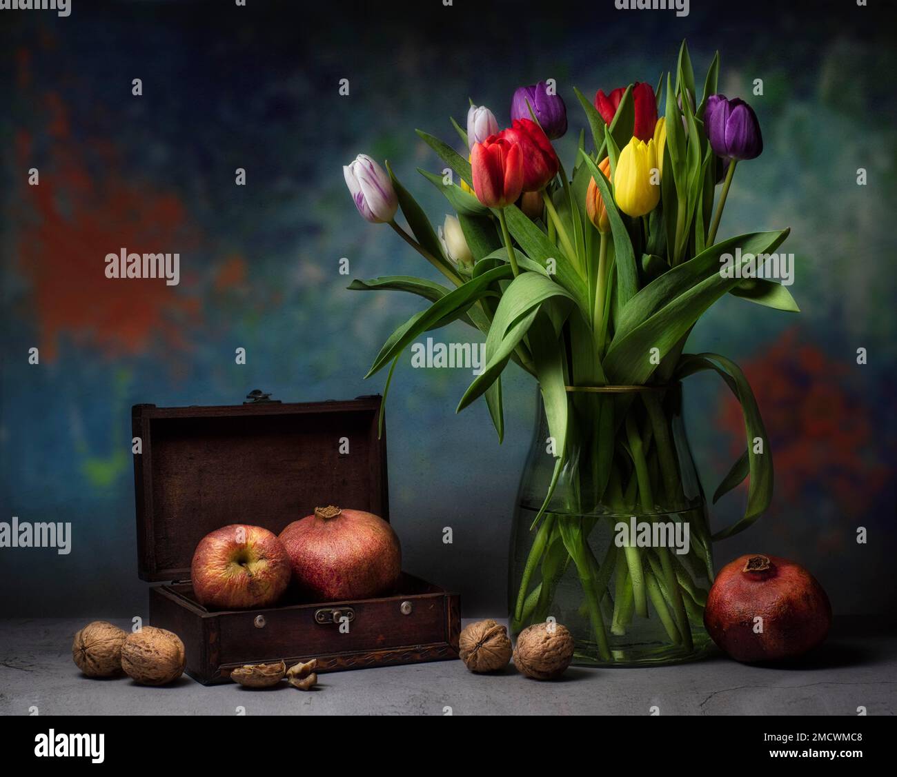 Still life with colourful bouquet of tulips in glass vase next to nuts ...