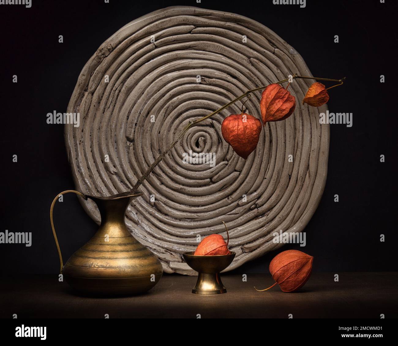 Theme Decoration, Mysticism, Still life with physalis in metal vase in front of round pottery coaster, Studio shot, Symbol photo Stock Photo