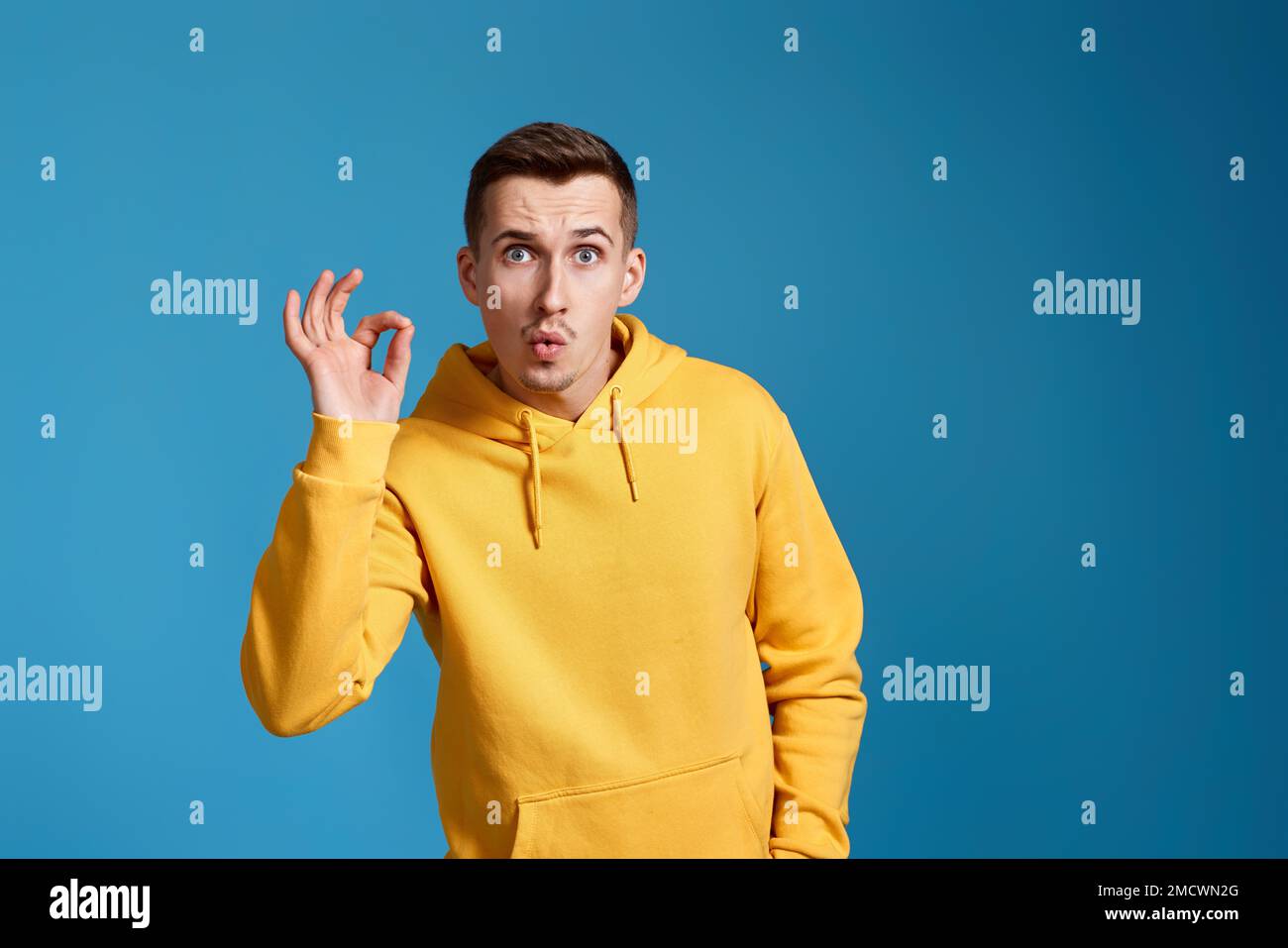 young man in yellow sweatshirt showing Ok gesture Stock Photo