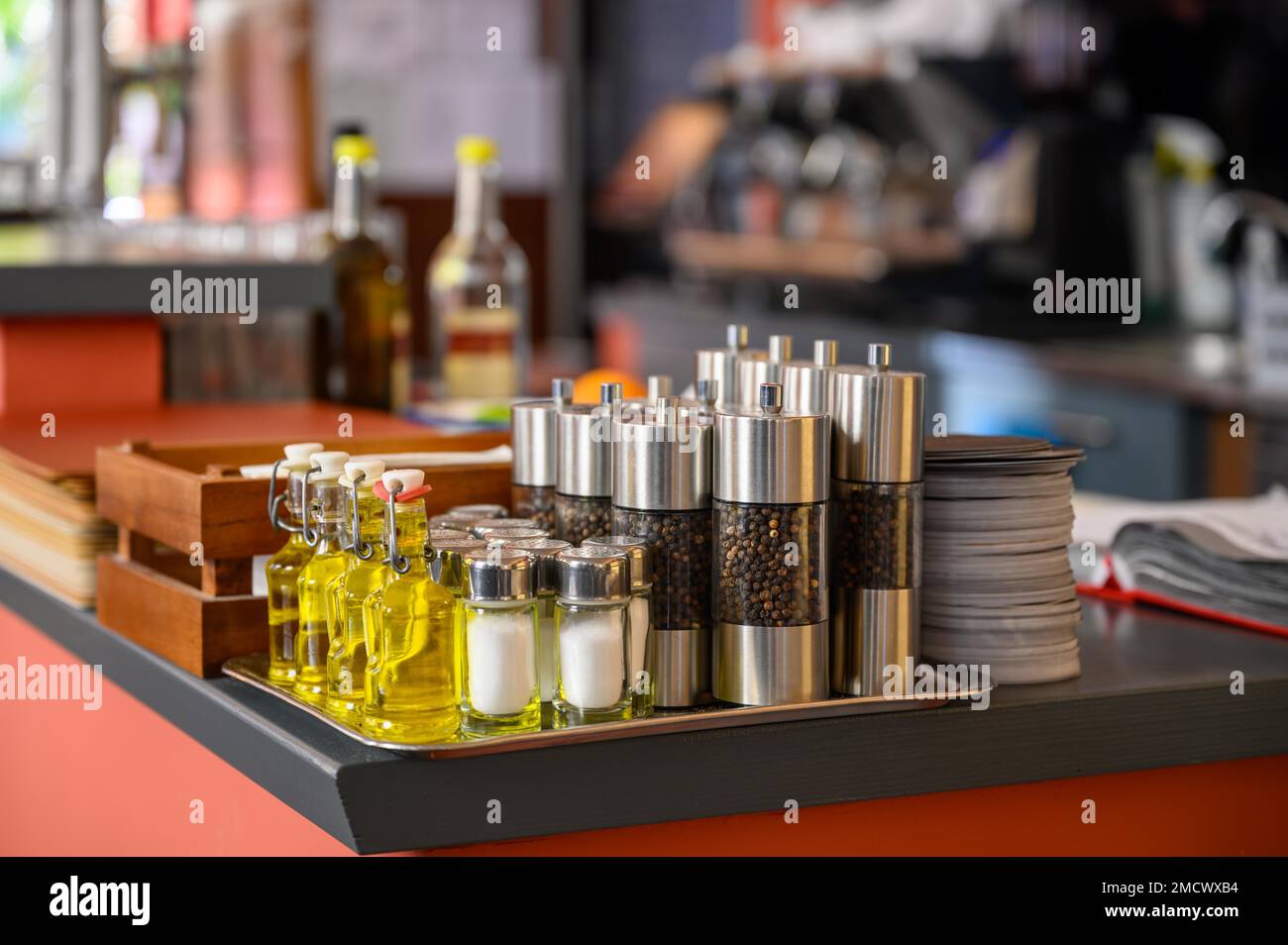 Salt and pepper shakers and small bottles of olive oil are placed on the counter of a restaurant Stock Photo