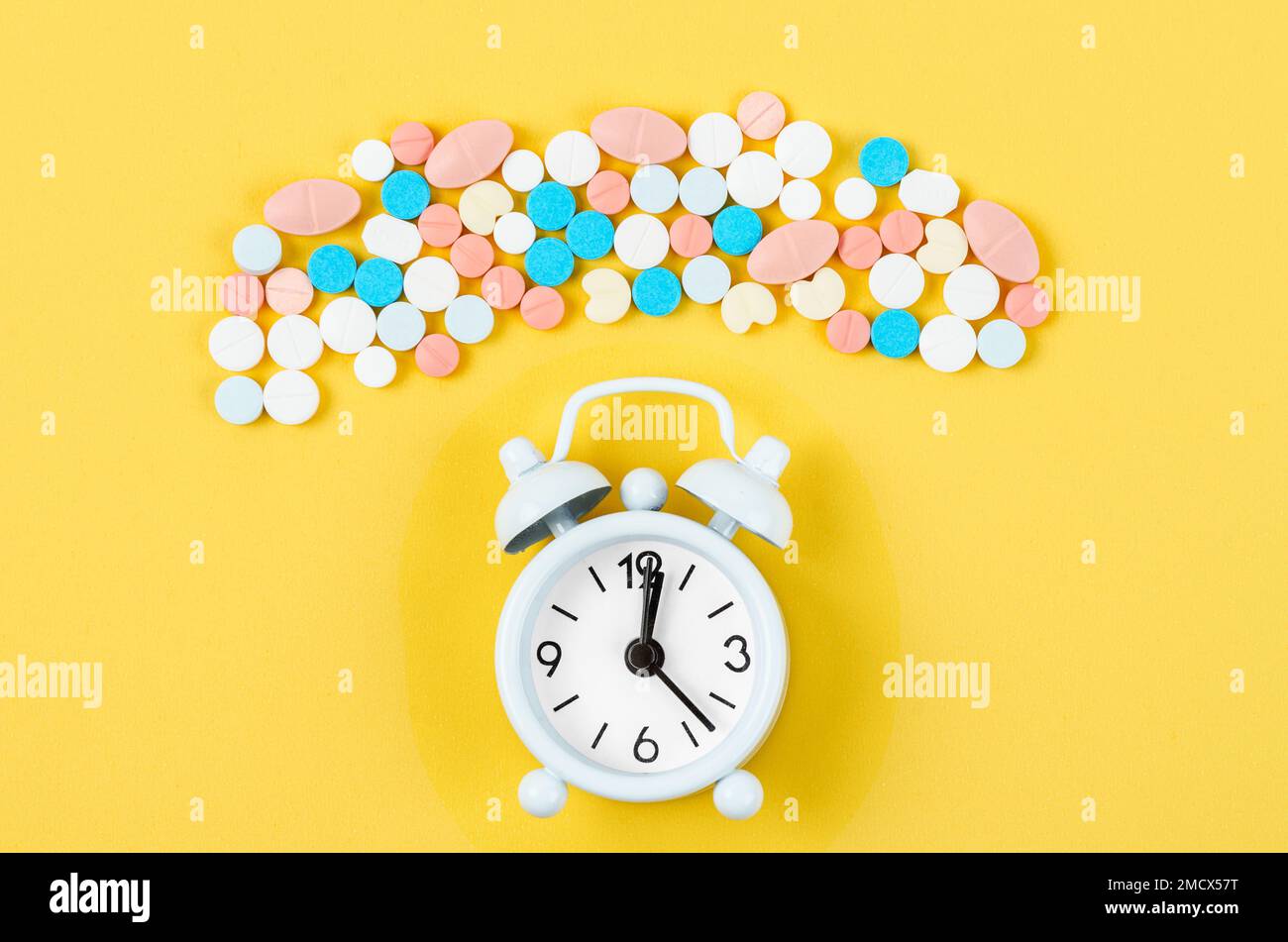 Alarm clock and many drug on a yellow background. Taking medicine at