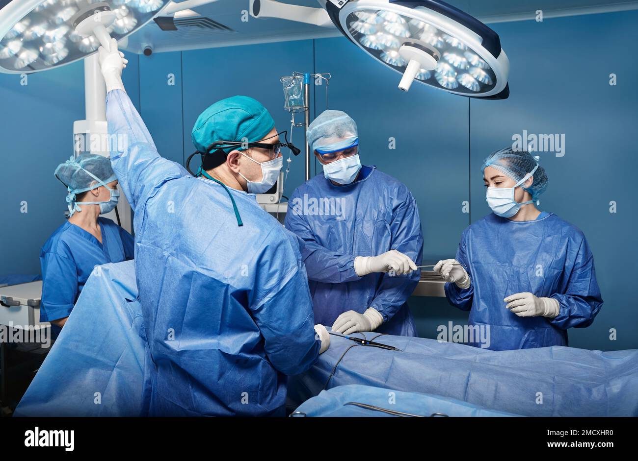 Team of surgeons and nurses performing surgical operation in hospital operating room. Surgery Stock Photo