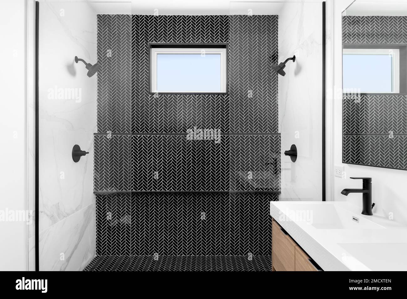A bathroom walkin shower with a black herringbone tiled wall and