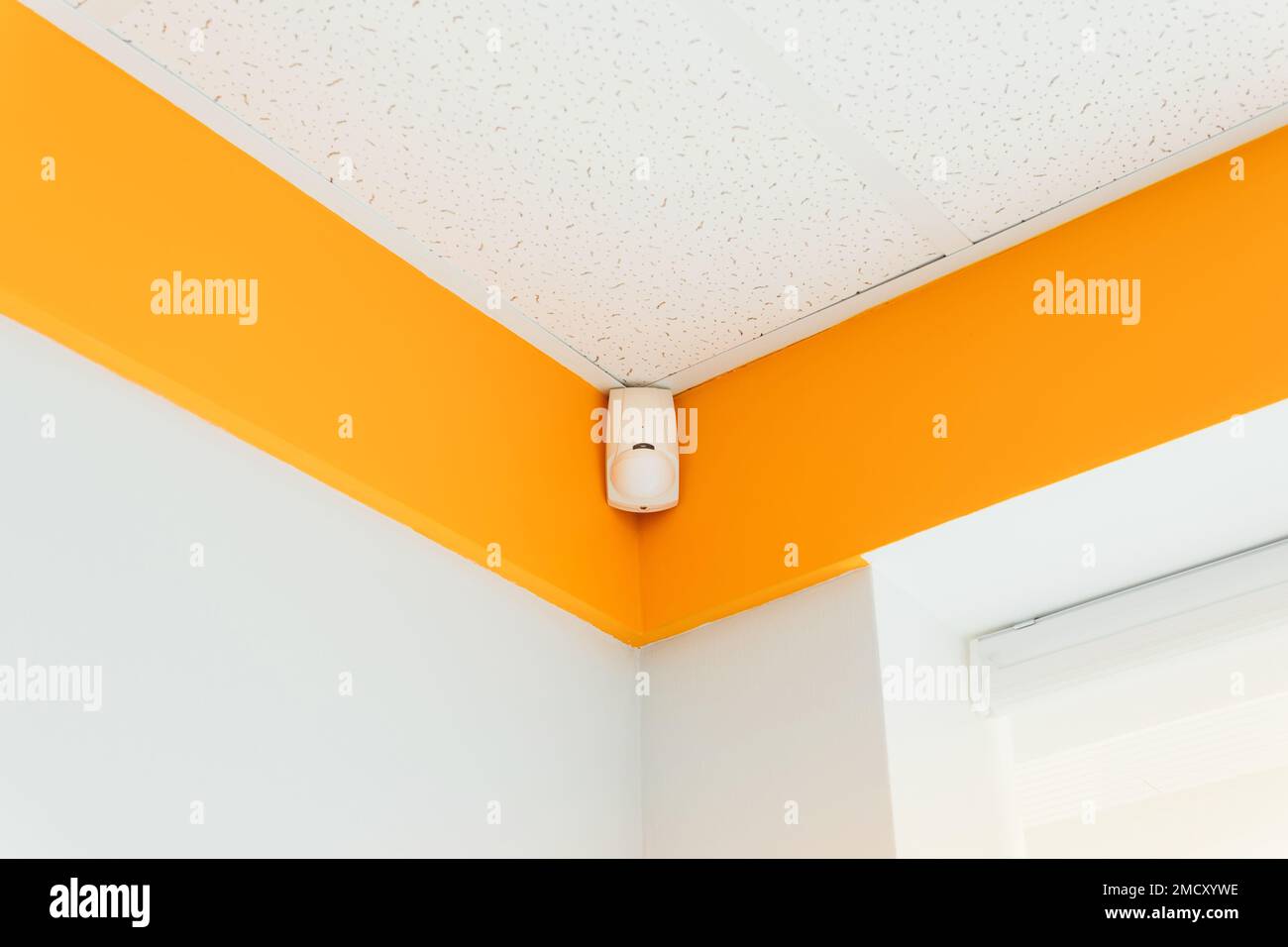 Combined motion or glass break sensor detector for security system mounted on wall in a hospital or house.  Stock Photo