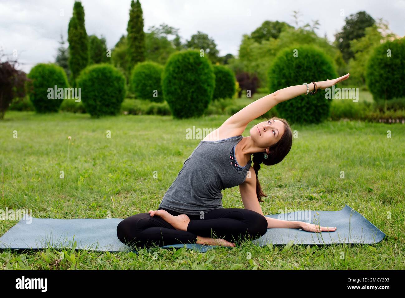 Caucasian woman, yoga instructor, doing side stretch, sitting spine