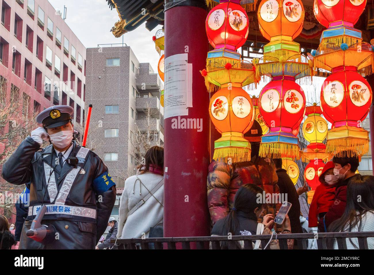 Yokohama, Japan. 22nd Jan, 2023. A Japanese police officer stands next to colourful lanterns during the Chinese Spring Festival Yokohama China Town, Kanagawa. Traditional Chinese cultural events to mark the lunar new year will happen in Yokohama's China Town from January 22nd to February 5th, 2023. Credit: SOPA Images Limited/Alamy Live News Stock Photo