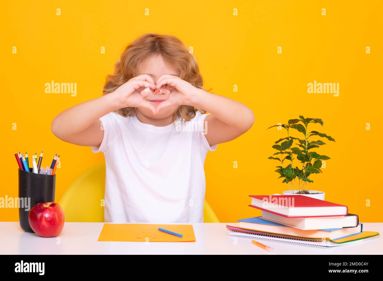 Pupil with love heard sign. Back to school. Funny little child from elementary school with book. Education. Kid study and learning. Stock Photo