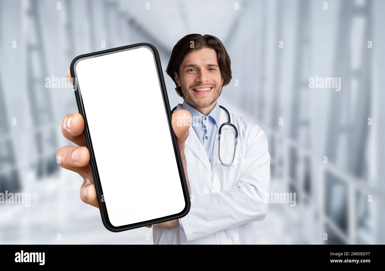 Handsome Male Doctor In Uniform Holding Big Blank Smartphone In Hand Stock Photo