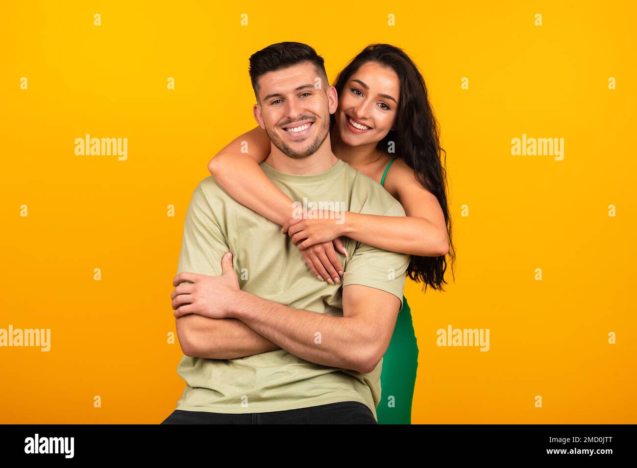 Happy young middle eastern lady in green dress hugging boyfriend, celebrate party event Stock Photo