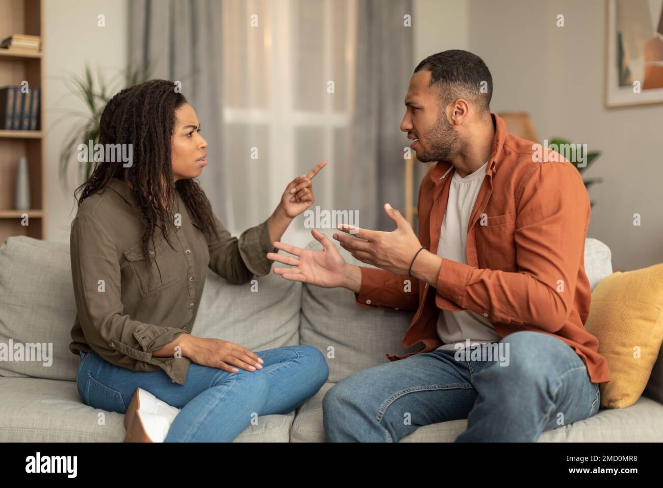 Emotional african american husband and wife sitting on couch, screaming ...