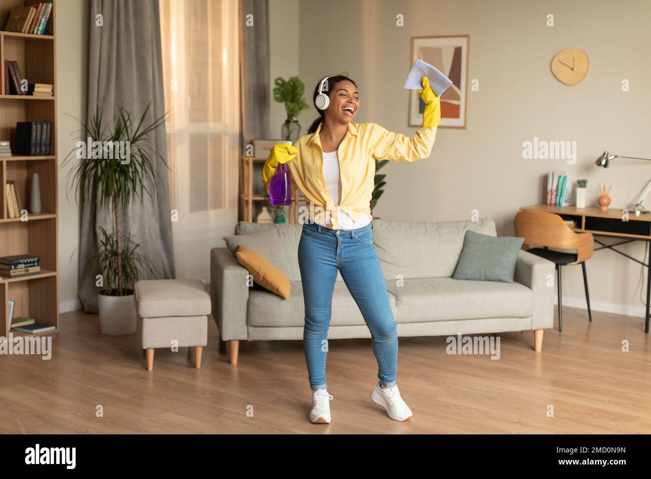 Cleaning is fun. Joyful black maid singing and dancing to music during