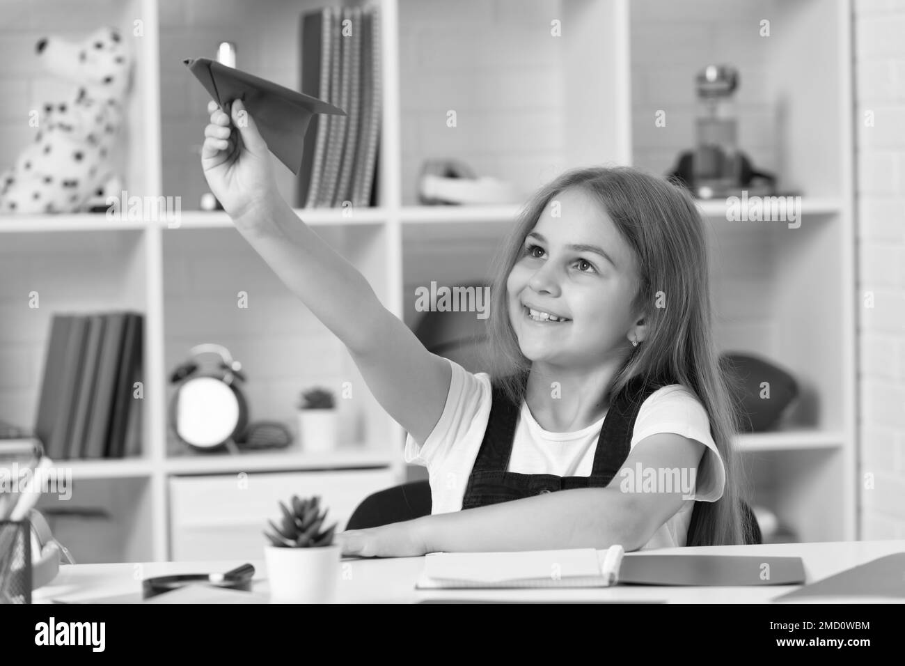cheerful kid play with paper plane in school classroom Stock Photo