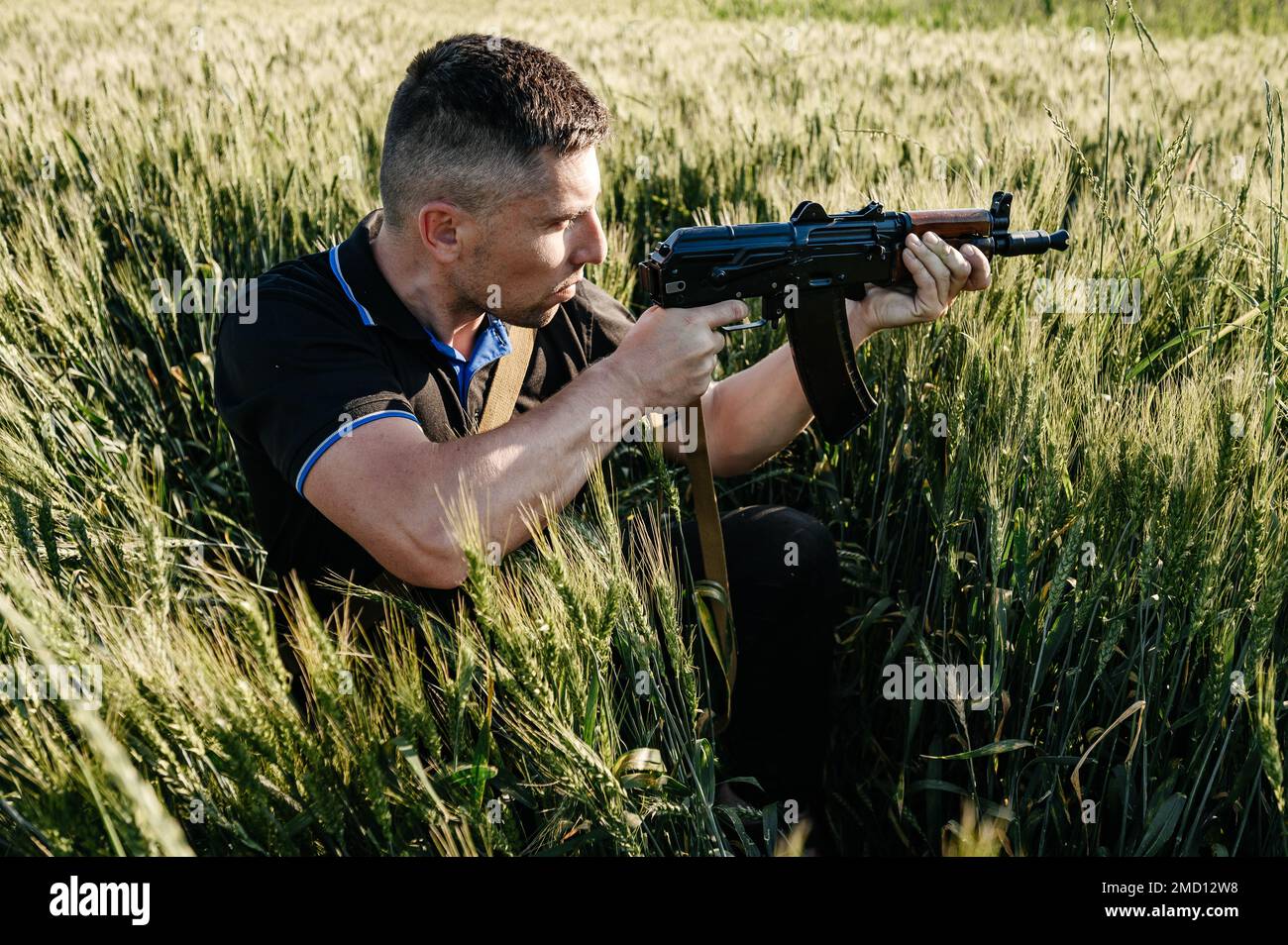 The man in the field with a machine gun, Ukrainian men are preparing for the war, Kalashnikov's automatic rifle. Stock Photo