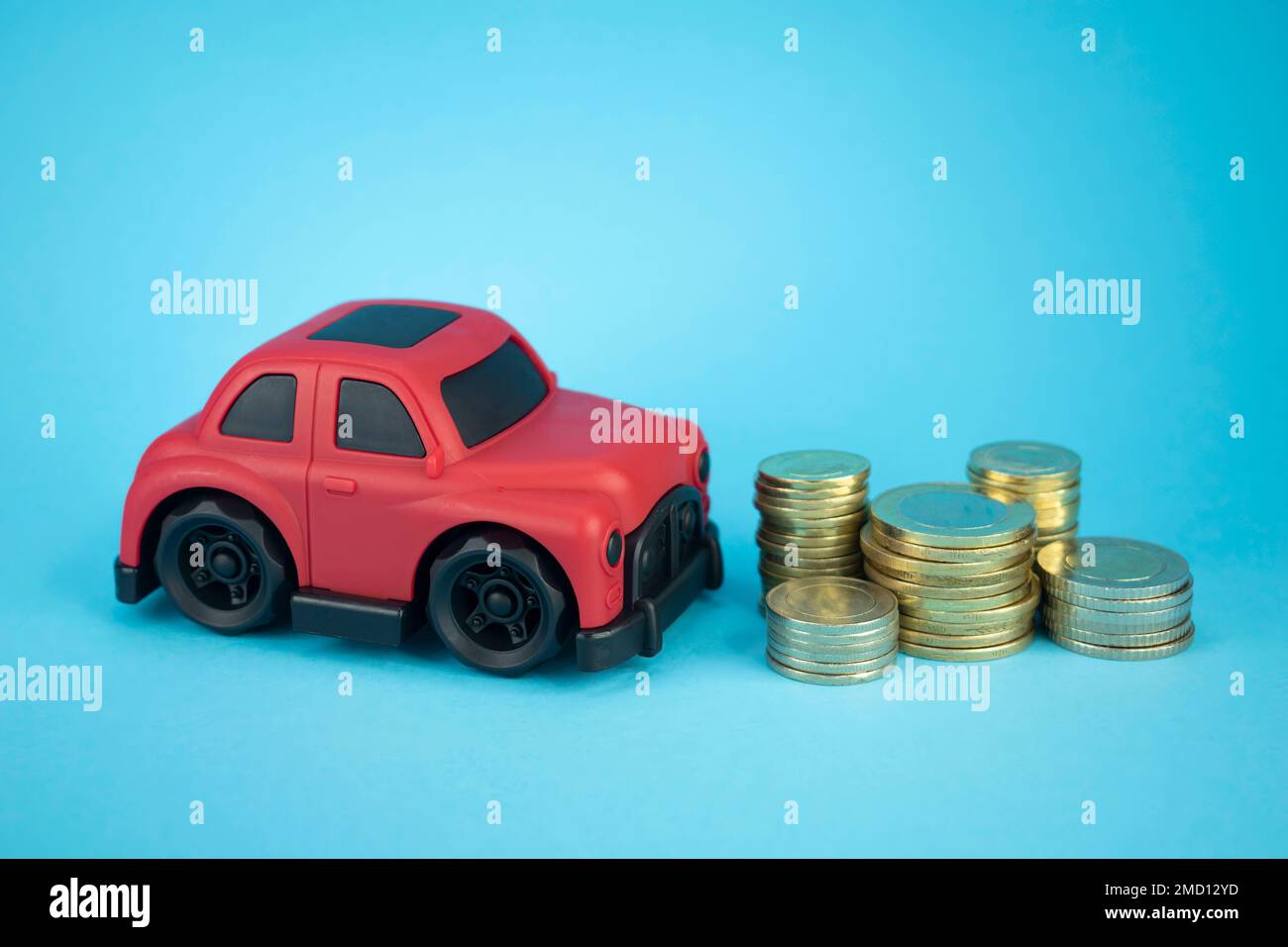 Toy car and coins on an isolated blue background Stock Photo