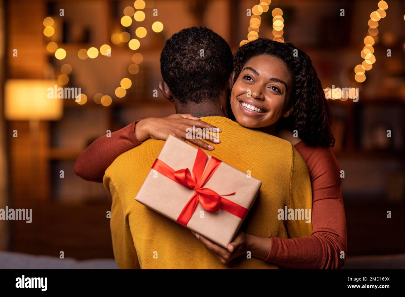 Thankful happy pretty black woman holding present and hugging man Stock ...