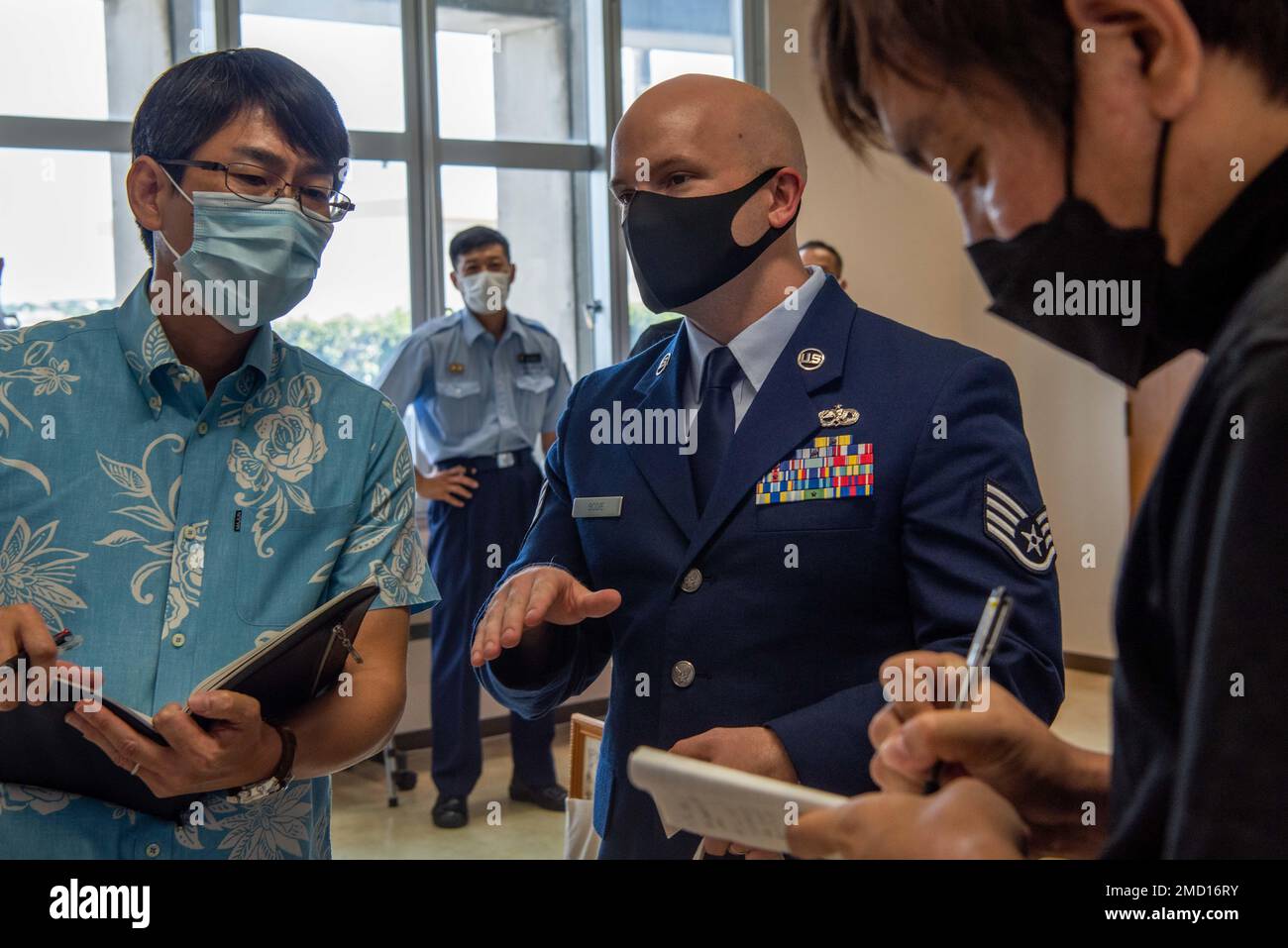 Jin Hiya, left, 18th Wing media relations specialist, interprets U.S. Air  Force Staff Sgt. Garrett Bodie, middle, 733rd Air Mobility Squadron support  NCO in charge, as he answers the questions of a