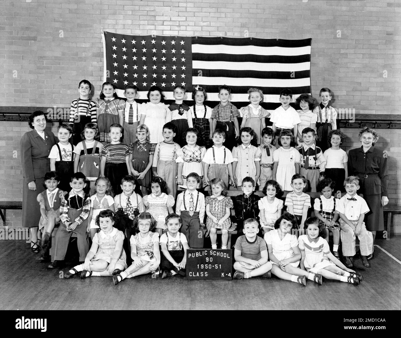 An archival photo of a 1950s classroom of posed students in front of the American Flag, 1950. Stock Photo