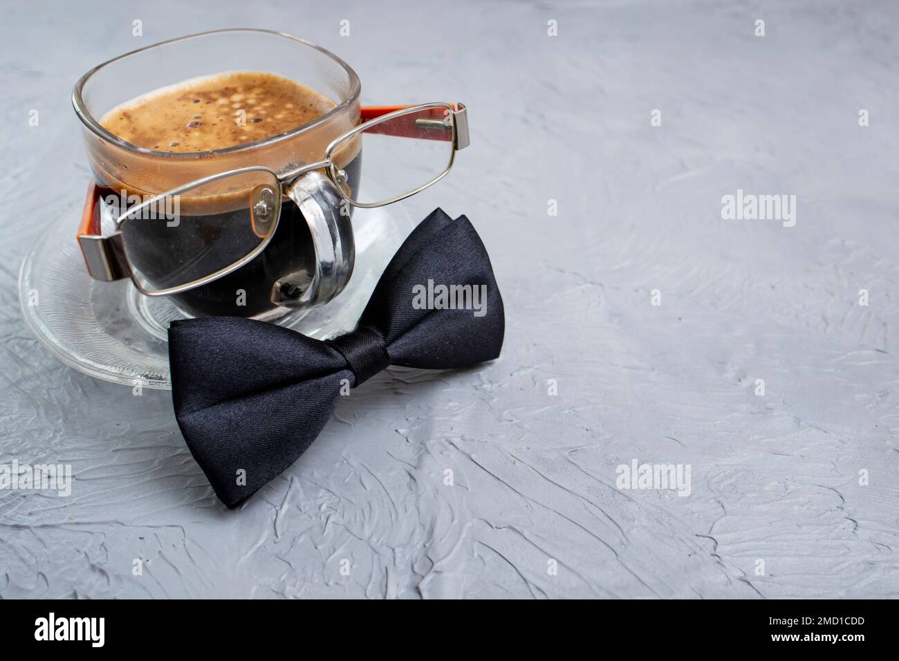 Transparent cup of coffee with eye glasses and black bowtie Stock Photo