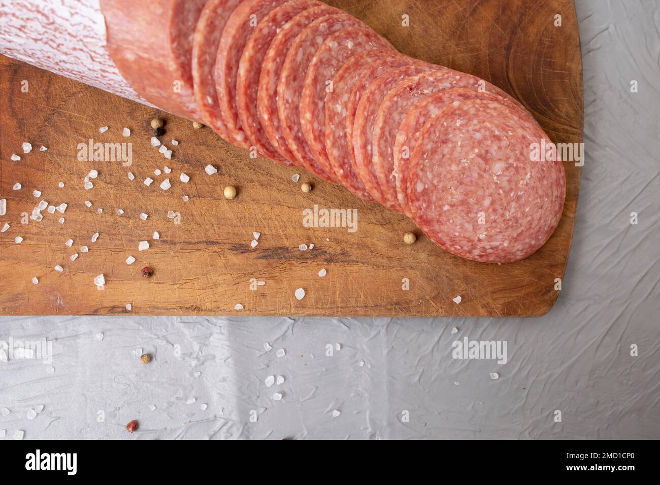 Thin sliced salami on a wooden chopping board, on cement table Stock Photo