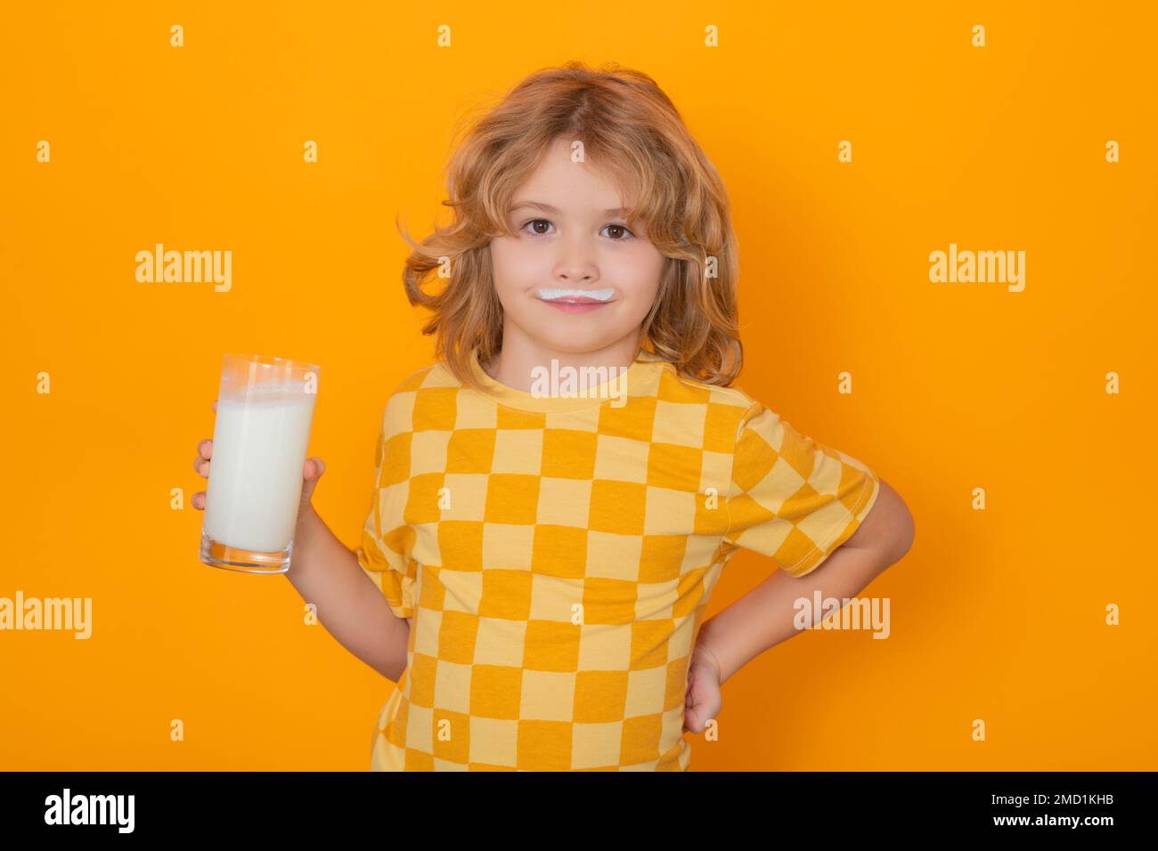 Kid drink fresh milk. Cute kid drinking milk on yellow background. Stock Photo