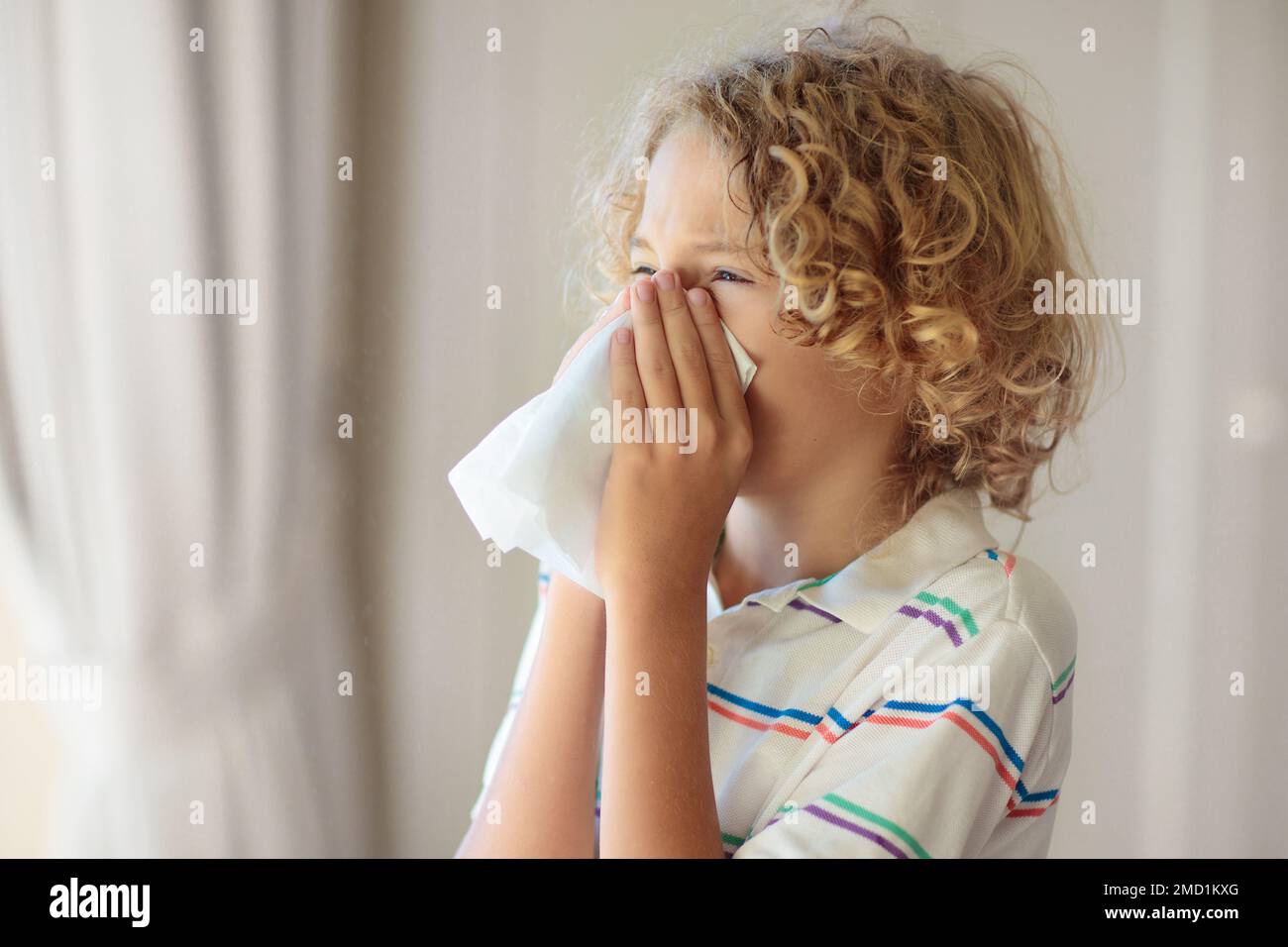 Sick child sneezing and coughing in paper tissue. Allergy treatment